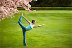 Woman in standing bow yoga position in park
