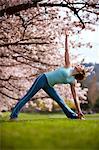 Woman in triangle yoga position by cherry tree