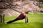 Woman in side angle yoga position under cherry tree