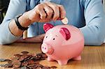 Senior woman inserting coins into piggybank