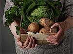 Woman holding wooden crate of vegetables