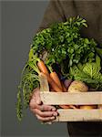 Man holding wooden crate of vegetables