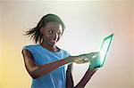 Teenage girl touching digital tablet with lights