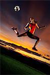 Female footballer in mid air against sunset