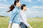 Two young women walking in field