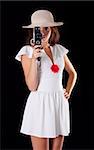 Young woman in white dress with vintage camera on black background