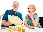 Senior couple shocked by the high cost of their medical bills.  White background.