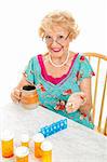 Smiling senior lady cheerfully takes her prescriptions and suppliments.  White background.