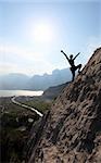 Silhouette of a female rock climber with outstretched arms, near Arco, North-Italy