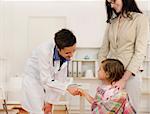 Pediatrician shaking hand with girl child patient at office