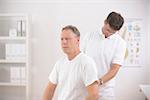 Physiotherapy: Physiotherapist examining senior man at office