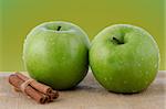 Two fresh green apples on green background.