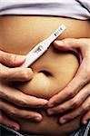 Male hand embrace pregnanct stomach while holding pregnancy test