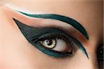 girl's eye closeup with creative green makeup, it looks at right