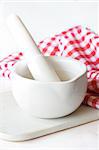 White ceramic mortar and pestle on a wooden board.