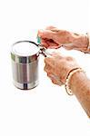 Closeup of elderly hands, with arthritis, struggling to use a can opener.  Isolated on white.