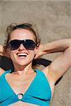 Portrait of smiling woman laying on sand beach