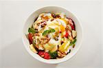 A fruit salad with yogurt and roasted pine nuts, seen from above