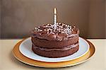 Ein Schokoladenkuchen, verziert mit silbernen Kugeln und eine Kerze