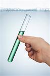 A hand holding a test tube of washing up liquid