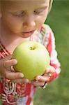Kleines Mädchen hält einen großen grünen Apfel