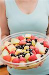 Woman holding large plastic bowl of fruit salad