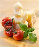 Tomatoes, basil and Parmesan on a wooden surface