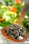 Graines de citrouille sur une cuillère à partir d'un bol de salade