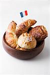 Croissants and sweet pastries with French flag in wooden bowl