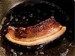 Frying a slice of pancetta (cured pork belly) in oil