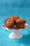 Three Sticky Cinnamon Rolls on a Small Pedestal Dish