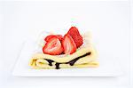 A pancake with chocolate sauce and fresh strawberries