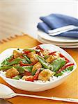 Chicken Stir Fry with Snow Peas and Red Peppers Over Rice in a Serving Bowl