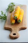 Three yellow courgettes on a chopping board