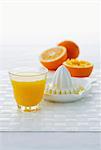 Un verre de jus d'orange, presse-agrumes citrus et oranges