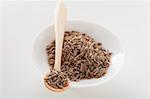 Cumin seed in a small bowl and on wooden spoon