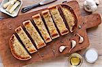 Garlic Bread Sliced on a Wooden Cutting Board; From Above; Ingredients for Garlic Bread