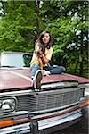 Young Woman Sitting on Car Hood