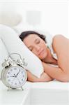 Close-up of a alarm clock with a woman sleeping