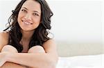 Close-up of a smiling young brunette sitting in her bed