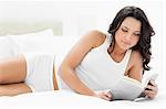 Attraktive Frau liest ein Buch auf ihrem Bett