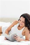 Nahaufnahme einer sexy Frau liest ein Buch auf ihrem Bett