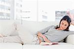 Brunette reading on her sofa