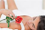 Brunette lying on her back with a rose