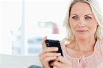 Close-up of a blonde with a mobile on a sofa