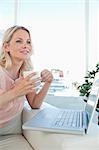 Smiling blonde on a laptop with a coffee