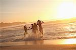 Young happy women dancing in the water at sunset