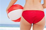 Close-up of a woman holding a beach ball against her hips