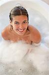 Smiling woman sitting in the tub and looking up