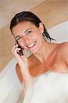 Smiling woman with her cellphone in the tub